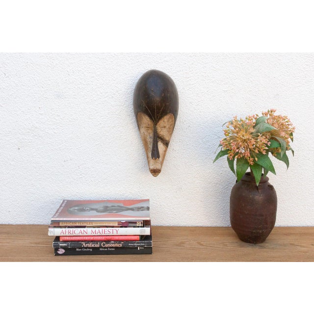 Discover the captivating allure of authentic African art with this vintage hand-carved wooden mask. Imbued with a rich...