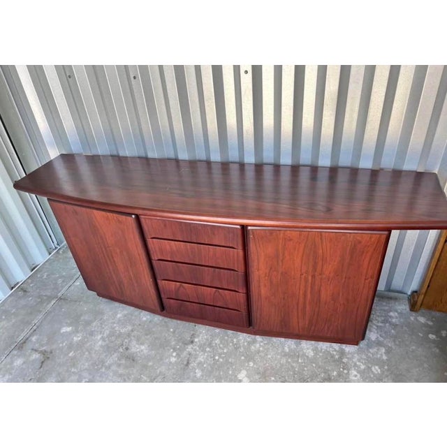 Skovby sideboard featuring a gently curved front, an overhanging top with rounded edges, and a recessed plinth base. Five...