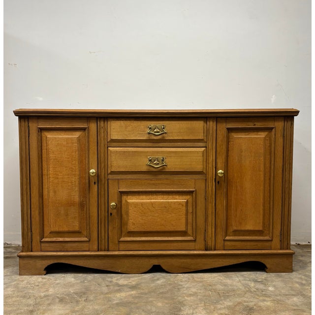 This 19th century English oak sideboard is a beautifully grounded example of traditional craftsmanship, rich with...
