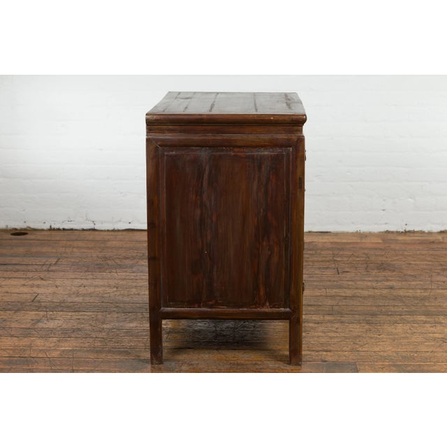A Chinese late Qing Dynasty period bedside cabinet from the early 20th century with four drawers and double doors. This...
