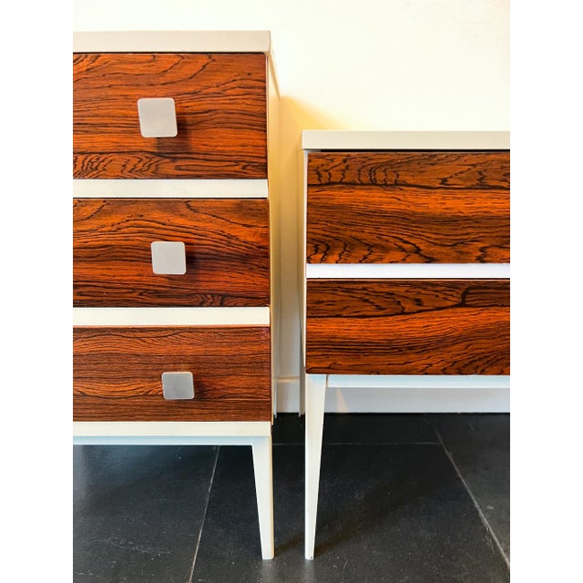 Two stunning vintage bedside tables from the 60s/70s in a design of white wood with rosewood veneer on a white metal...