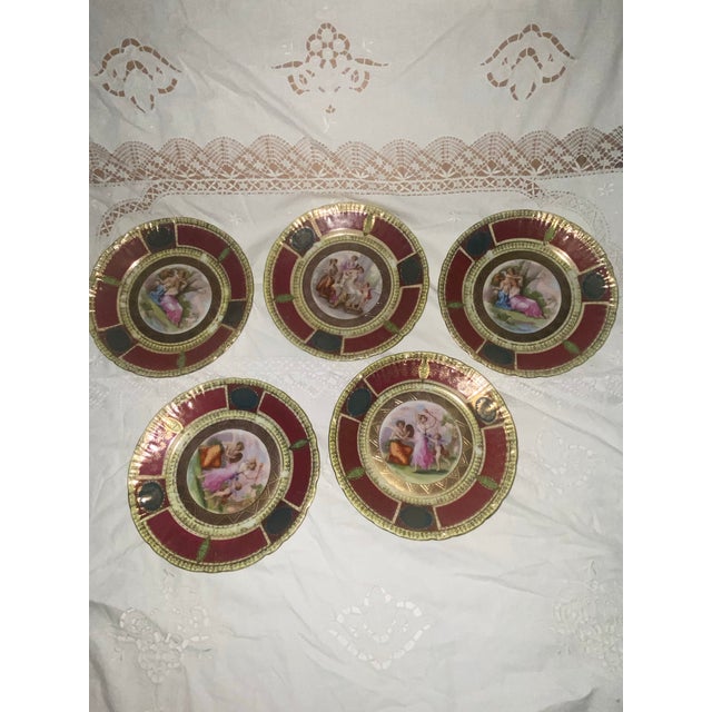 An exquisite set of five (5) antique Royal Vienna style porcelain cabinet plates, showcasing a striking crimson (maroon)...