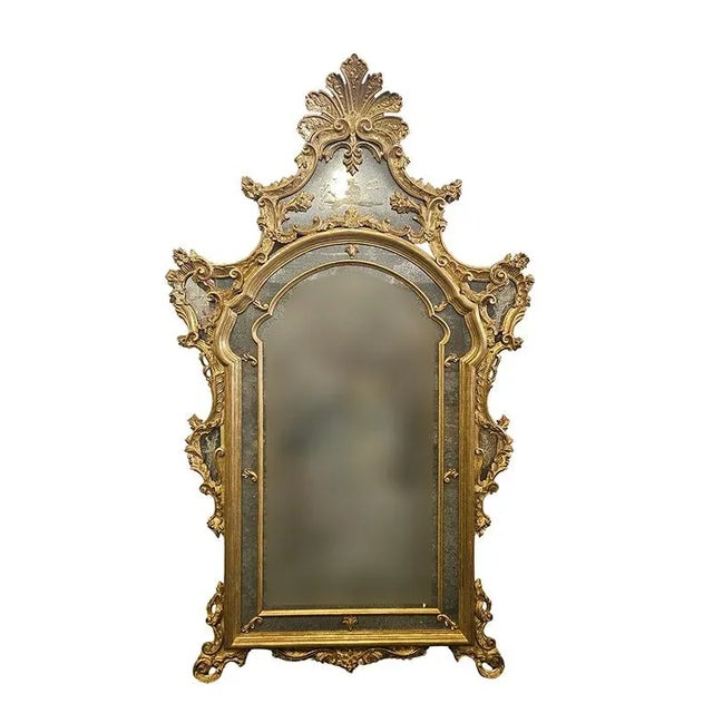 Large gilded wood mirror with a shaped frame carved with plant and scroll motifs, and an acid-etched upper mirror with a...