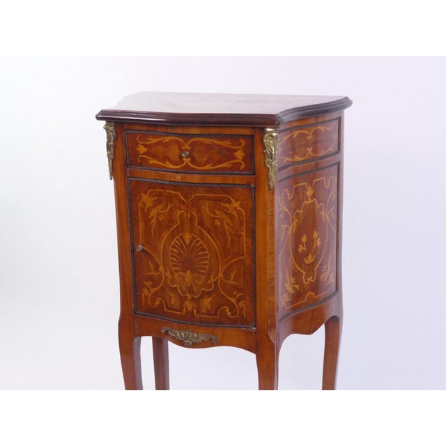 An amazing antique English lacquered side table decorated with floral inlay as well as brass details. The nightstand has...