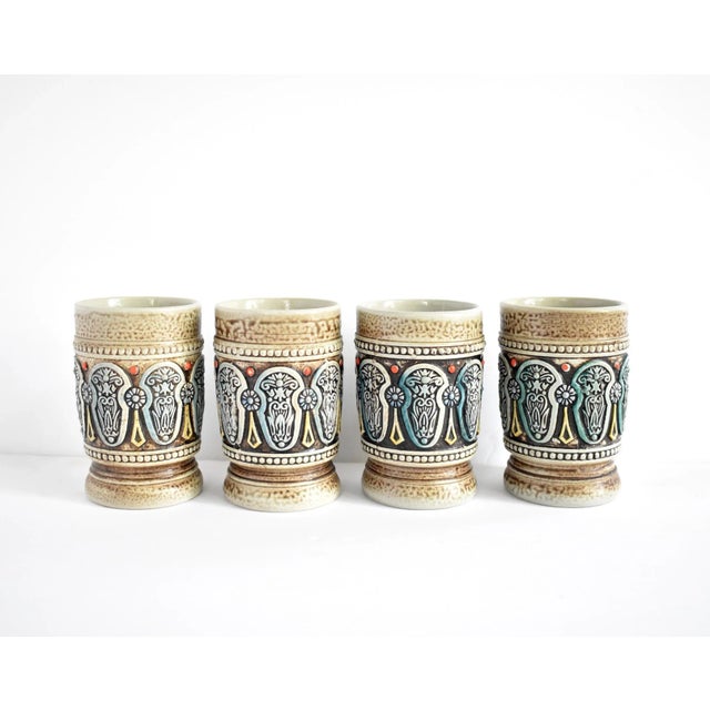 A set of 4 West German ceramic tumblers, mid-century, with intricate embossed designs of blue and orange, on a mottled...
