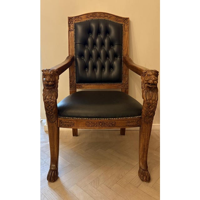 Hand-Carved wooden armchair with lion head armrests and intricate floral motifs. The chair is upholstered in luxurious...