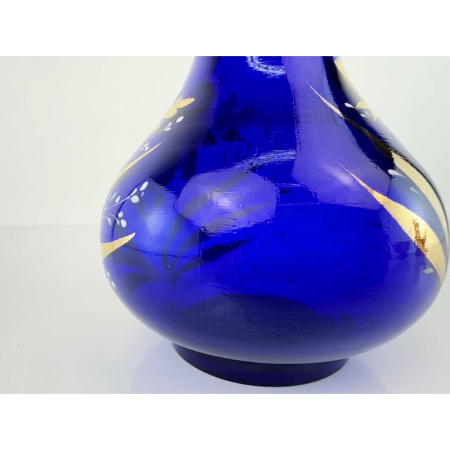 This striking vintage Czech glass vase features an elegant cobalt blue base with hand-painted gold floral motifs. The gold...
