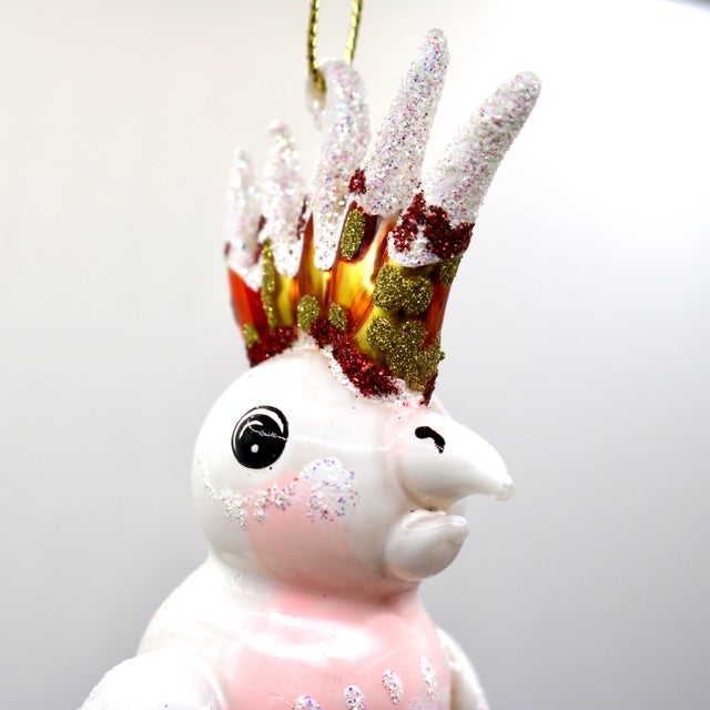 Bring whimsical elegance to your holiday display with this striking, hand-painted mouth-blown glass cockatoo ornament....