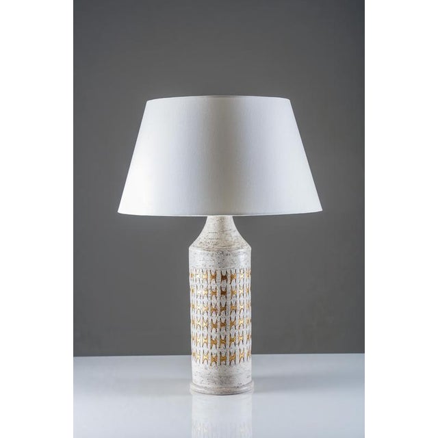 Pair of table lamps featuring ceramic bases produced by bitossi and mounted by bergboms during the 1970s. The cylindrical...