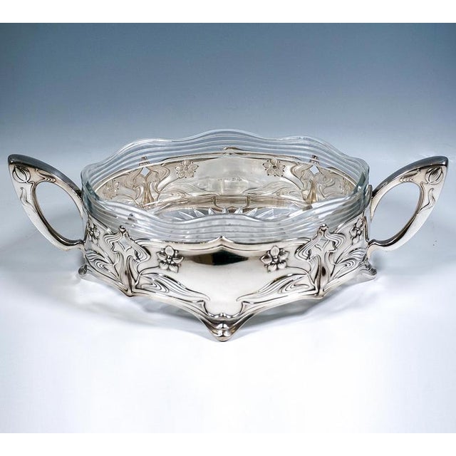 Decorative silver jardiniere with an oval floor plan, standing on four downward-curving feet, the sides featuring curved...