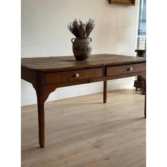 A long English farm table in pine, gone a deep honeyed brown on the plank top with the old chatter and splits you want in...