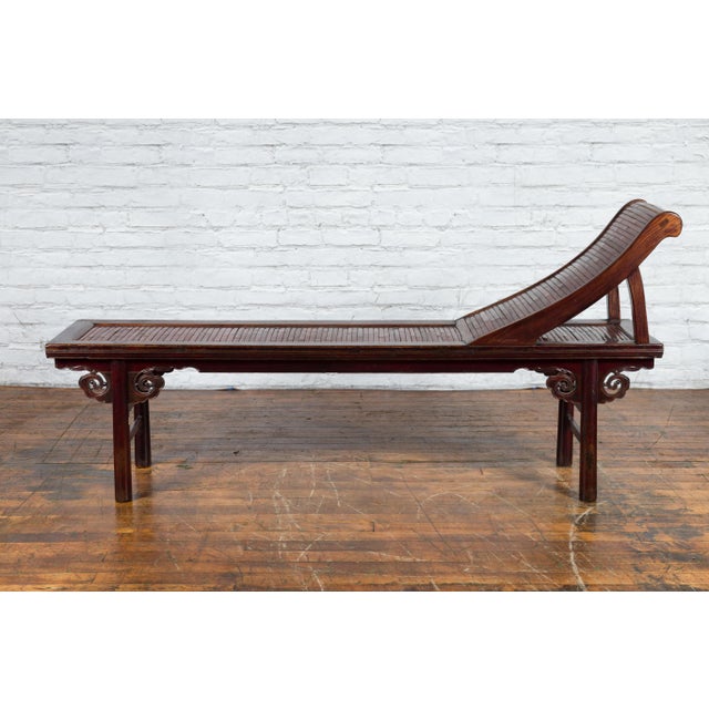 A Chinese Qing Dynasty period elm wood reclining lounge chair from the 19th century with bamboo slats and cloud-themed...
