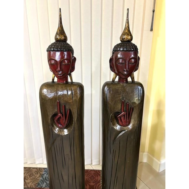 A vintage pair of extra tall, wooden, standing Buddha statues—send a message of peace, tranquility and spirituality at the...