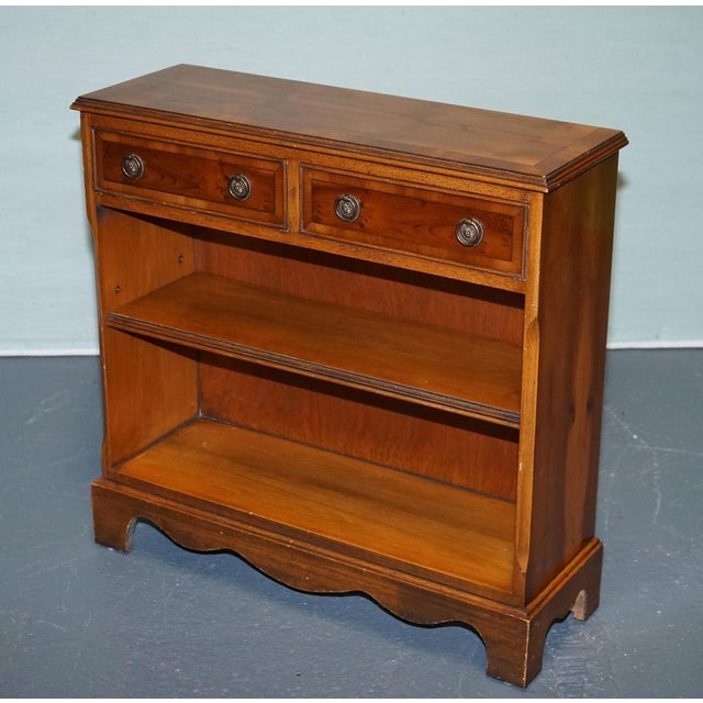 Antiques of London Elegant vintage yew wood low bookcase featuring two upper drawers with traditional brass handles and...