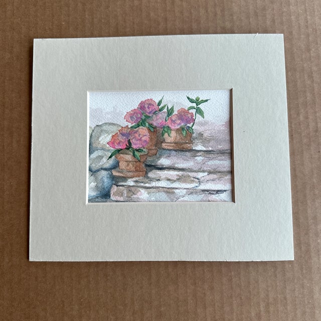 This artwork portrays a charming scene with potted pink flowers placed on stone steps. The warm earthy tones of the...