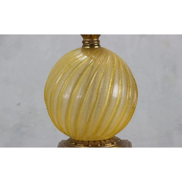 This Italian Murano table lamp combines a ribbed globe of luminous gold glass with a finely carved giltwood stem and base,...