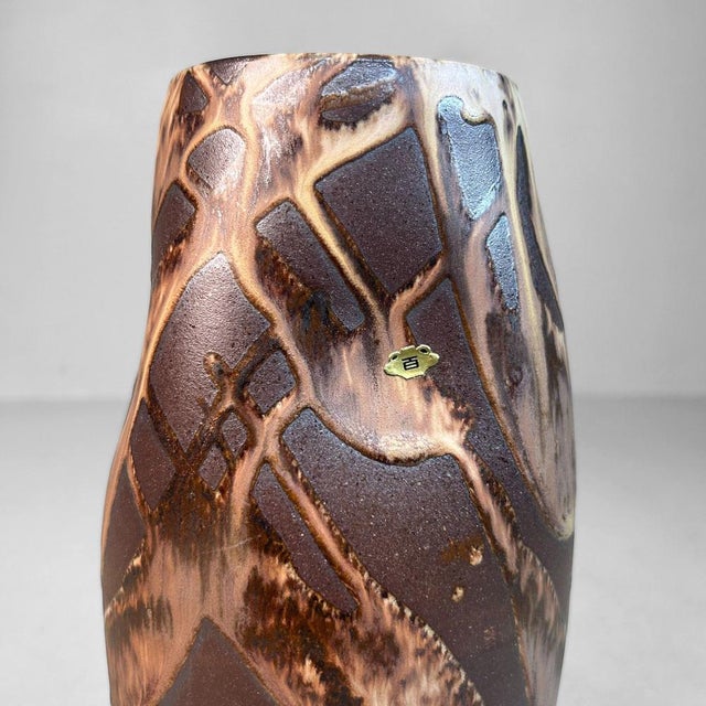 A sculptural, slender ikebana vase in dark brown Shigaraki stoneware. The subtle curves in its form enhance the elegant...