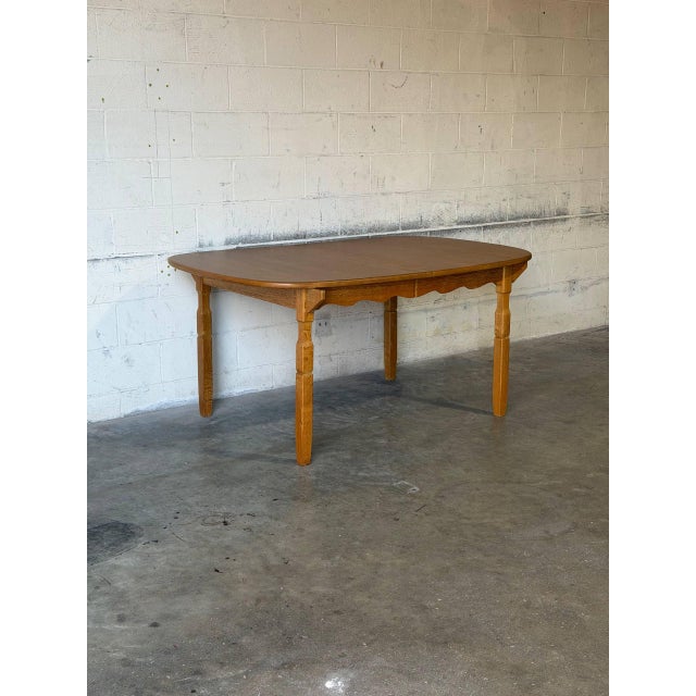 This extendable dining table features an oval top, scalloped apron details, and elegant turned legs. It includes three...
