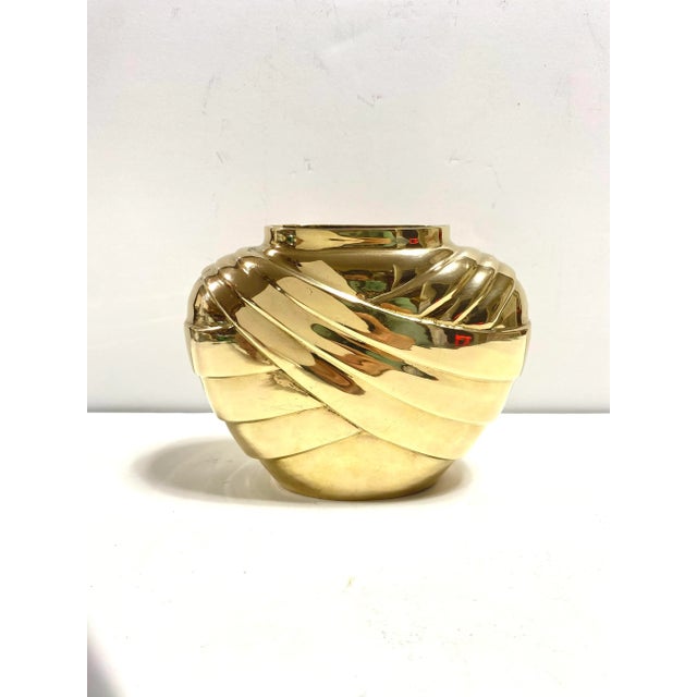A striking solid brass vase featuring sculptural Art Deco-inspired curves and rich golden finish. Brass vessels like this...