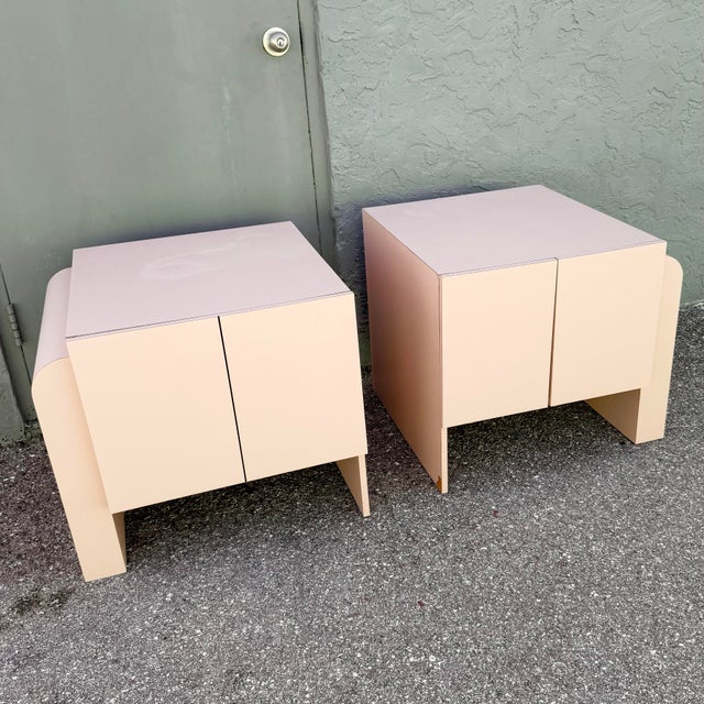 Striking pair of vintage nightstands or side cabinets featuring a soft blush pink laminate finish and sculptural Art Deco...