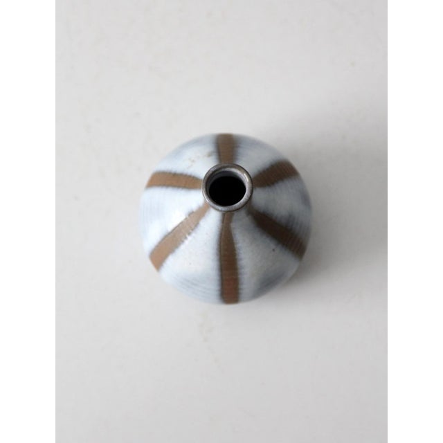 Small handmade studio pottery vase with a softly rounded body and bottle-neck silhouette. Finished in a blue-gray glaze...