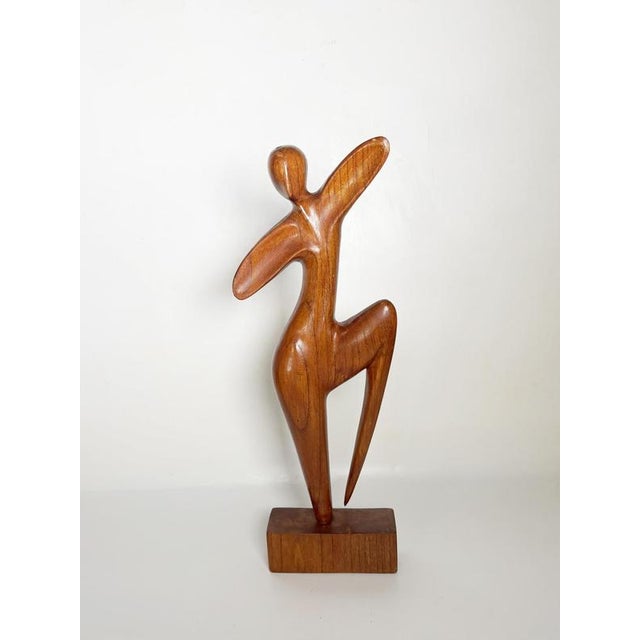 Elegant abstract wooden sculpture depicting a stylized female figure in a graceful dancing pose. Hand-carved from solid...
