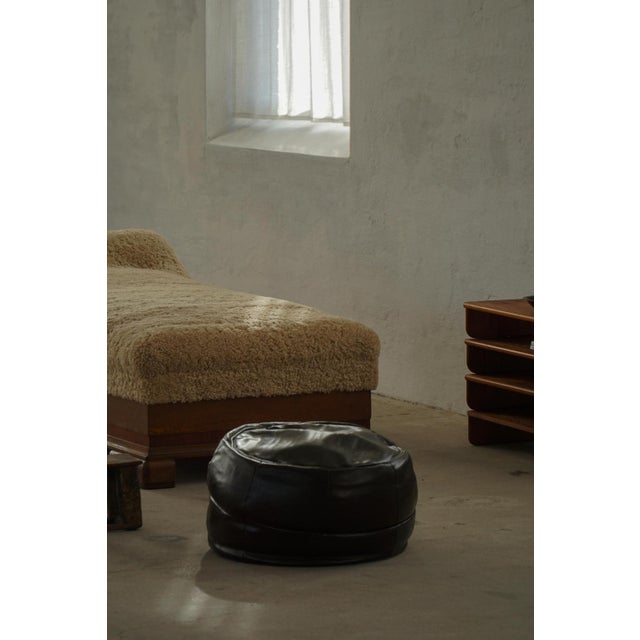 A leather pouf featuring a soft, slouchy silhouette and relaxed sculptural form. The pouf is upholstered in supple leather...