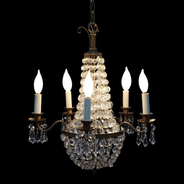 This vintage Italian chandelier, dating to approximately 1950, features a brass frame adorned with numerous cut crystal...