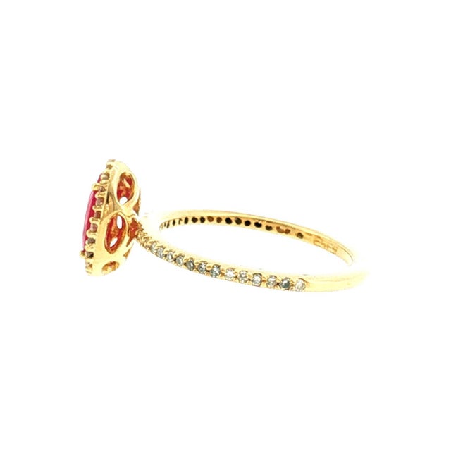 A late 20th-century 14k gold ring featuring a 6x8mm oval synthetic ruby, surrounded by a halo of single-cut natural...