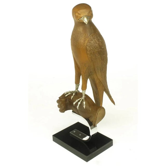 Wonderfully carved falcon or hawk, mounted on a carved wood hand. Silver talons and beak. All surmounted on a C shaped...