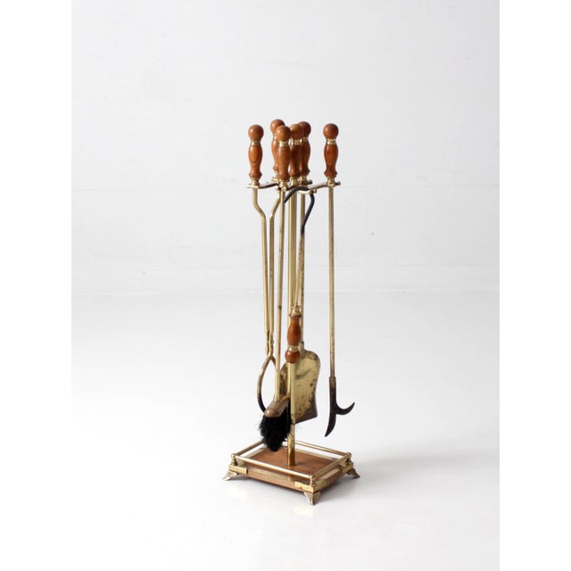A vintage Hollywood Regency fireplace tool set dating to the 1960s, crafted in a sophisticated mix of polished brass and...