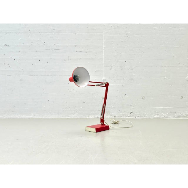 A striking 1970s desk lamp with classic industrial design and a movable spring mechanism. The bright red metal shade and...