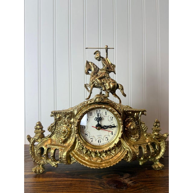 An elegant vintage brass mantel clock in the ornate Rococo Revival style, dating to the mid-to-late 20th century. Inspired...
