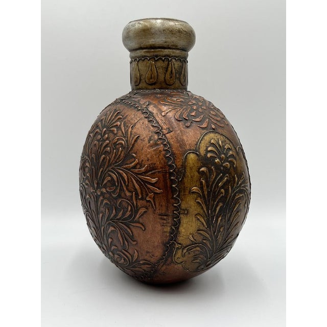 This tin vessel made of copper impresses with its harmonious shape and a finely crafted floral pattern that runs elegantly...