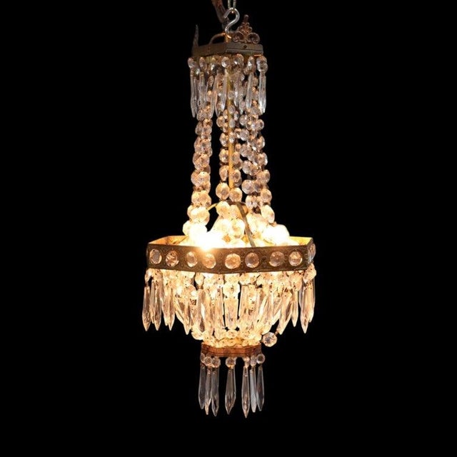 This vintage Italian chandelier, dating to approximately 1950, features a brass frame adorned with elegant cut crystal...