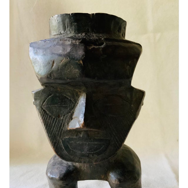 A carved wood ceremonial cup from West Africa, entirely hand-carved of a single wood with no inlay, standing upright on...