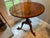 A vintage round accent table with an inlaid starburst marquetry top and carved pedestal tripodal base. Product...