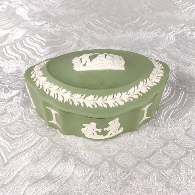 This is an oval Wedgwood jasperware covered trinket box in Celedon. The base is shaped with higher sides than the middle...