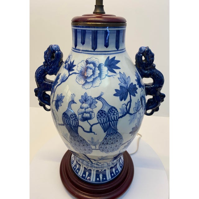 Pair of Blue and White Chinoiserie Porcelain Urn Table Lamps with Peacock Motifs and Dragon Handles A striking pair of...