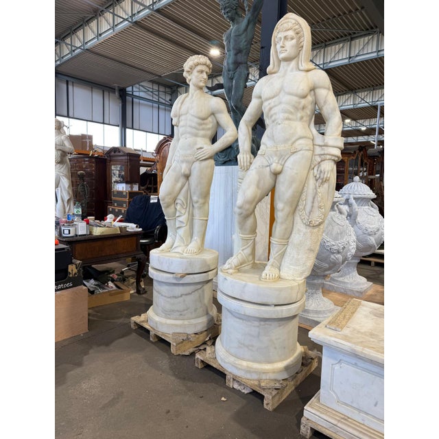 An exceptional pair of solid Carrara marble figures, masterfully sculpted with elegant proportions and intricate...