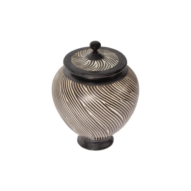 A studio pottery lidded vessel by American artist Brian Moore. This piece is covered in a black and white wavy line design...