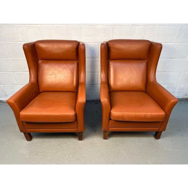 A striking pair of mid-century modern brown leather lounge chairs crafted by Wiels Møbler in Denmark. These chairs feature...