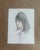 A softly rendered portrait featuring a doe-eyed figure with voluminous hair and subtle pastel accents. The gentle shading...
