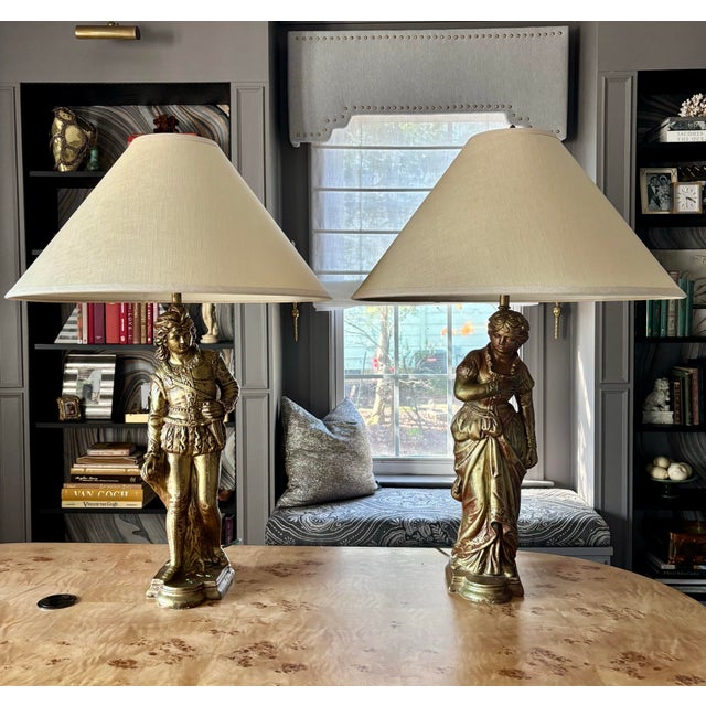 Striking pair of large figural table lamps in hand-painted, antiqued gilt over heavy ceramic base. With original matching...