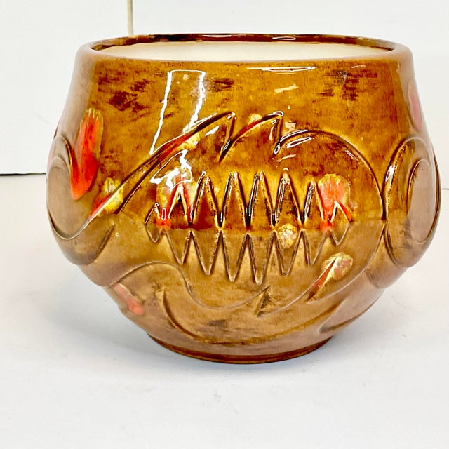 This American Folk Art ceramic planter is finished in a rustic Southwestern palette of browns and orange splatter. The...