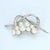 This brooch features a cluster of eight lustrous pearls, elegantly arranged. Curved bands encrusted with white diamonds...