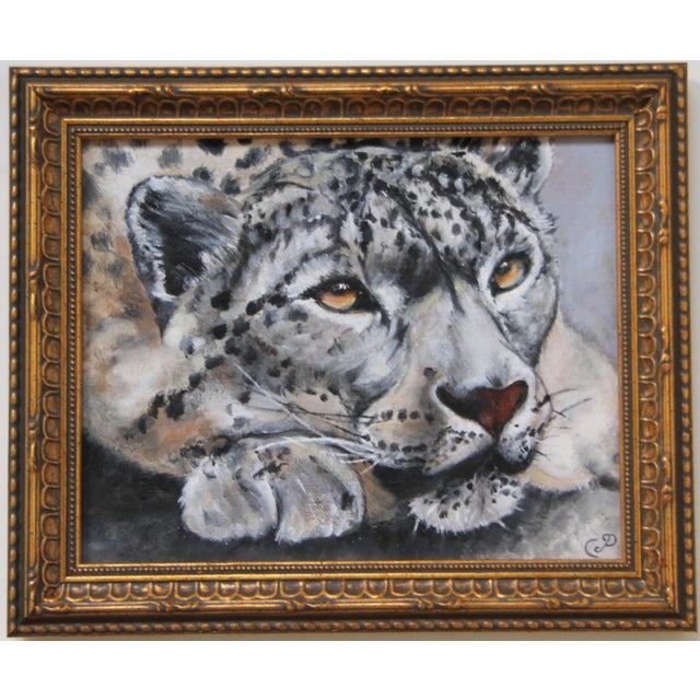 A golden eyed snow leopard portrait painted in a traditional realist style and framed in a quality ornately carved gold...