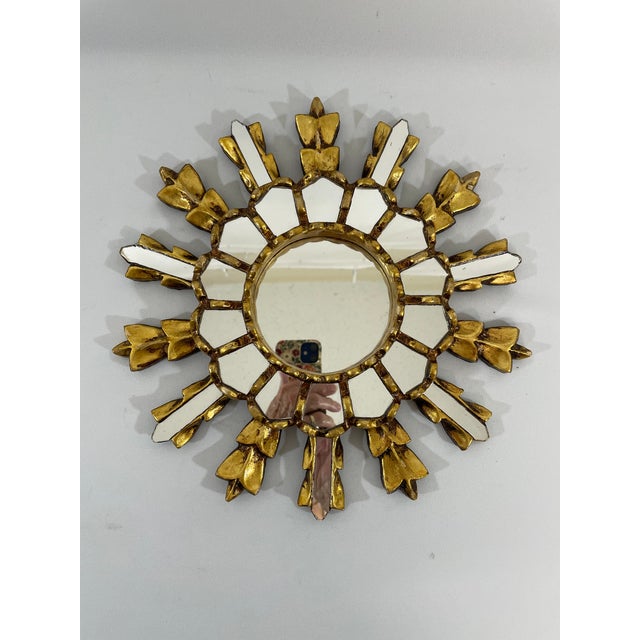 A splendid hand carved 12" French Giltwood Sunburst Wall Mirror, circa 1950s-60s. The central 3.5" flat mirror is framed...