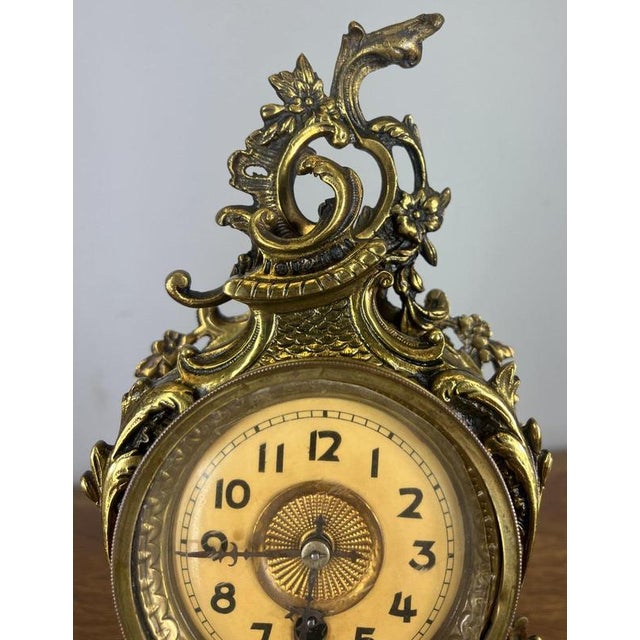 This Vintage French brass mantel clock is a richly ornate decorative piece, featuring elaborate scrolling forms and...