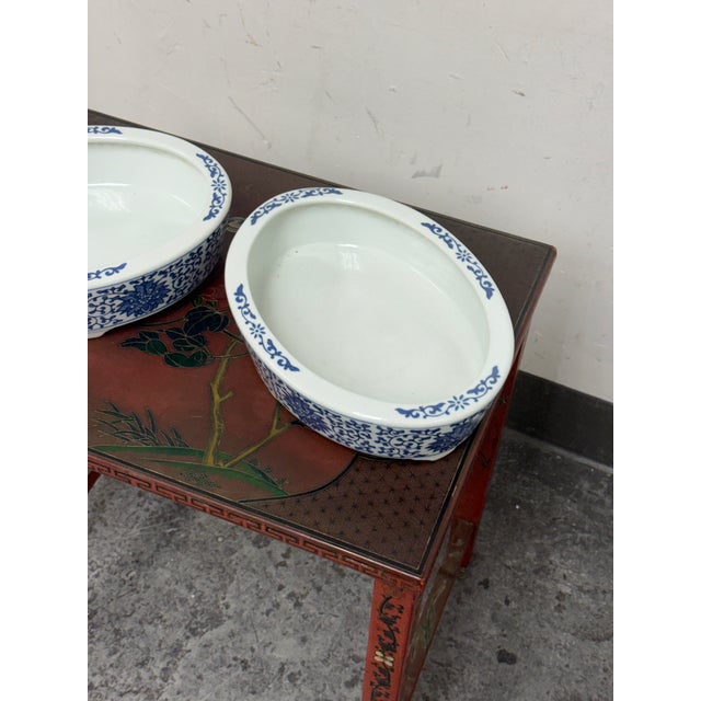 Design Plus Gallery presents a Pair of Blue + White Chinoiserie Ceramic Oval Planters. This ceramic pair offers oval forms...